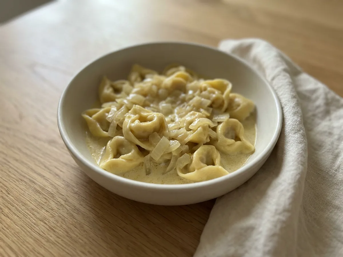 Symbolbild zum Rezept Zwiebel Sahne Tortelloni: das fertige Gericht auf einem hellen Teller angerichtet